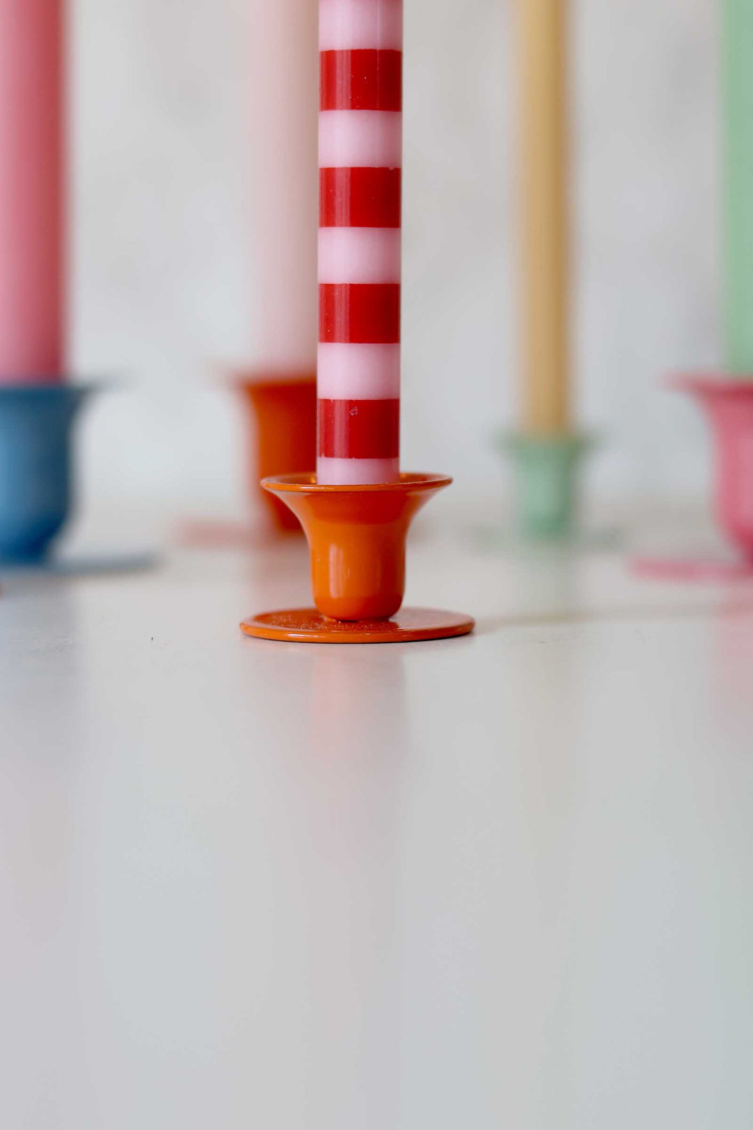 Colorful candle holders with candles on a white surface