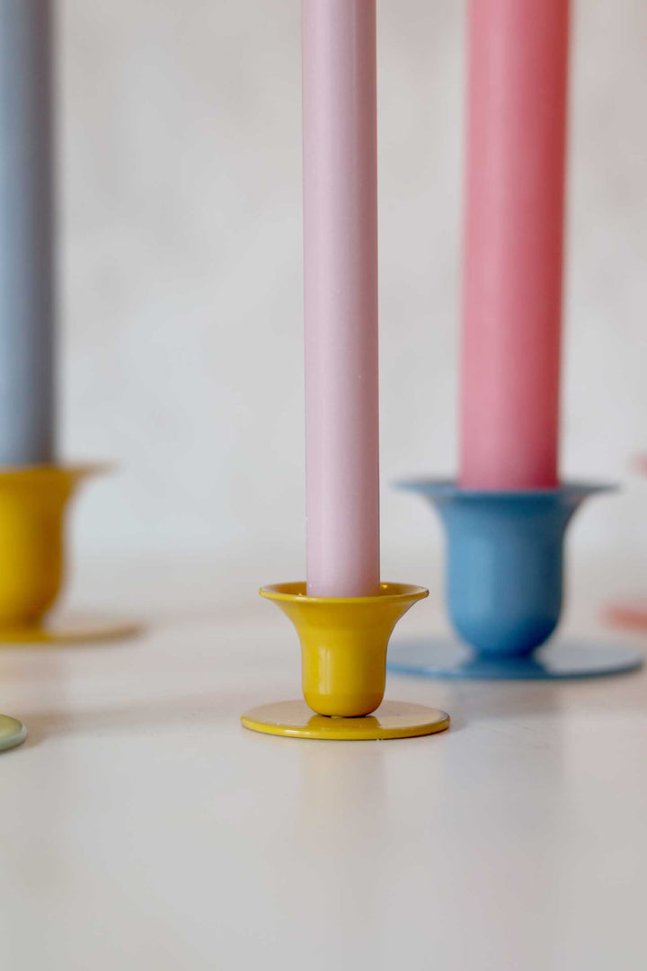 Colorful candle holders with pink candles on a white surface