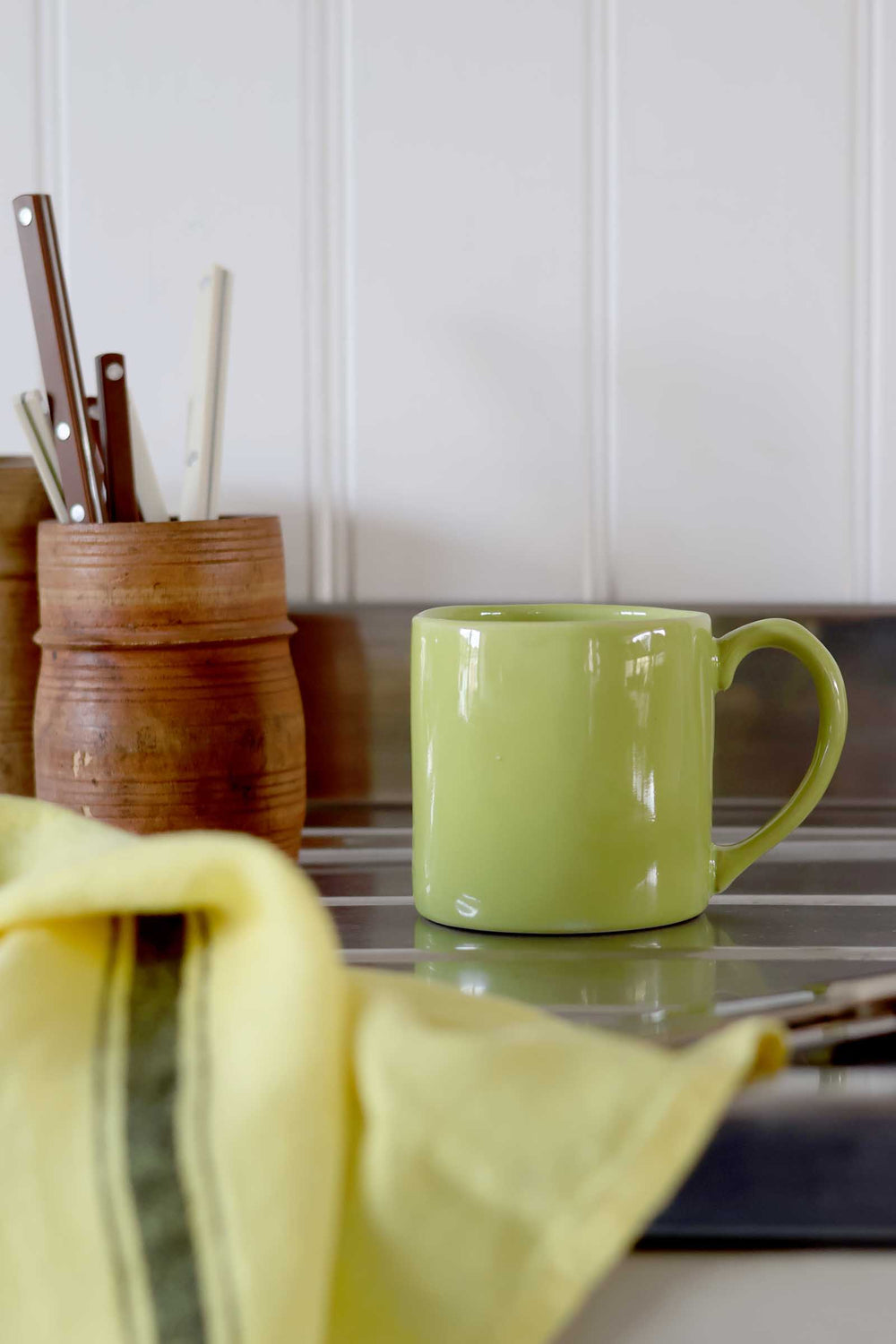 Green mug on a kitchen counter with utensils in the background