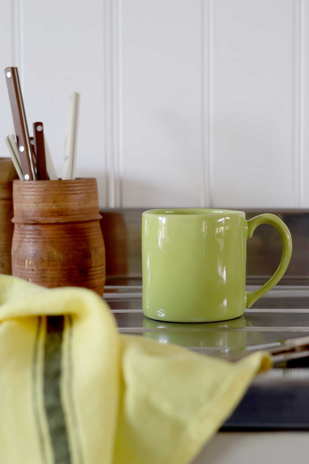Green mug on a kitchen counter with utensils in the background