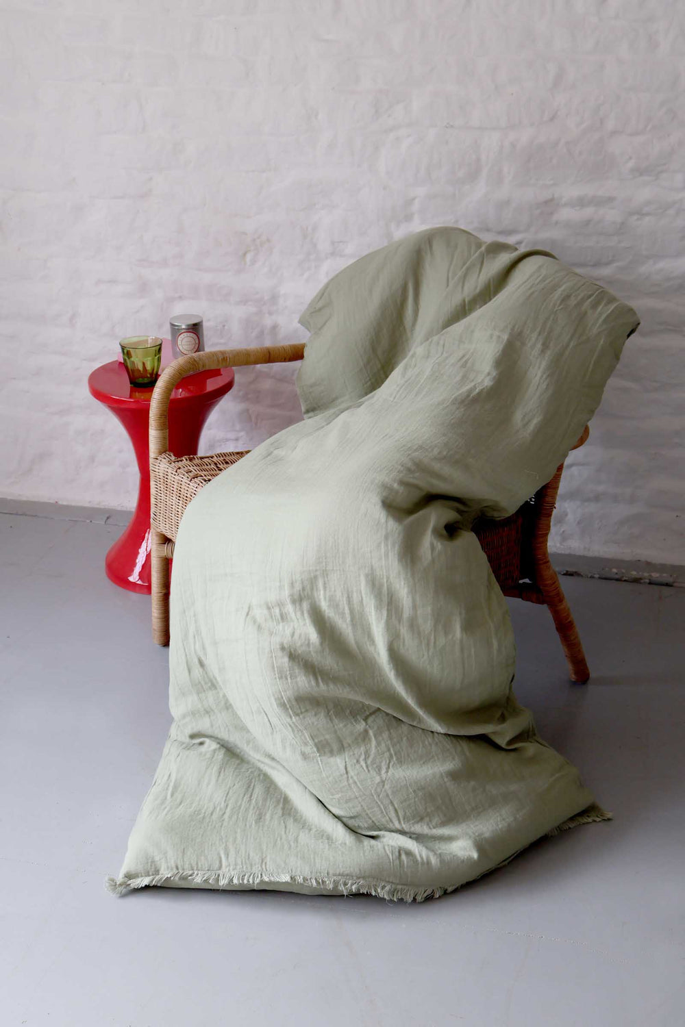 Light green fabric draped over a wicker chair against a white wall.