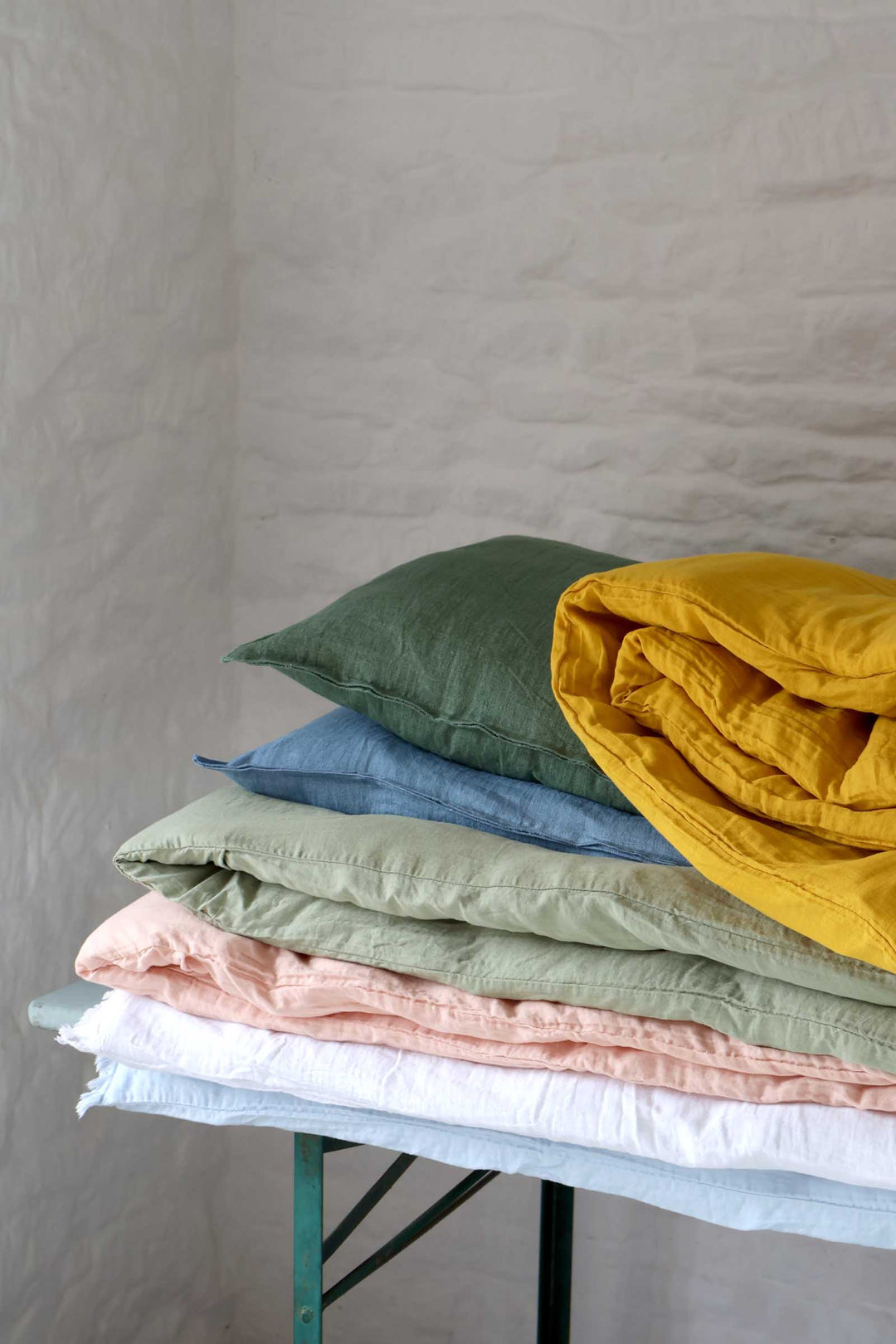 Stack of folded fabric pieces in various colors on a stand against a plain background