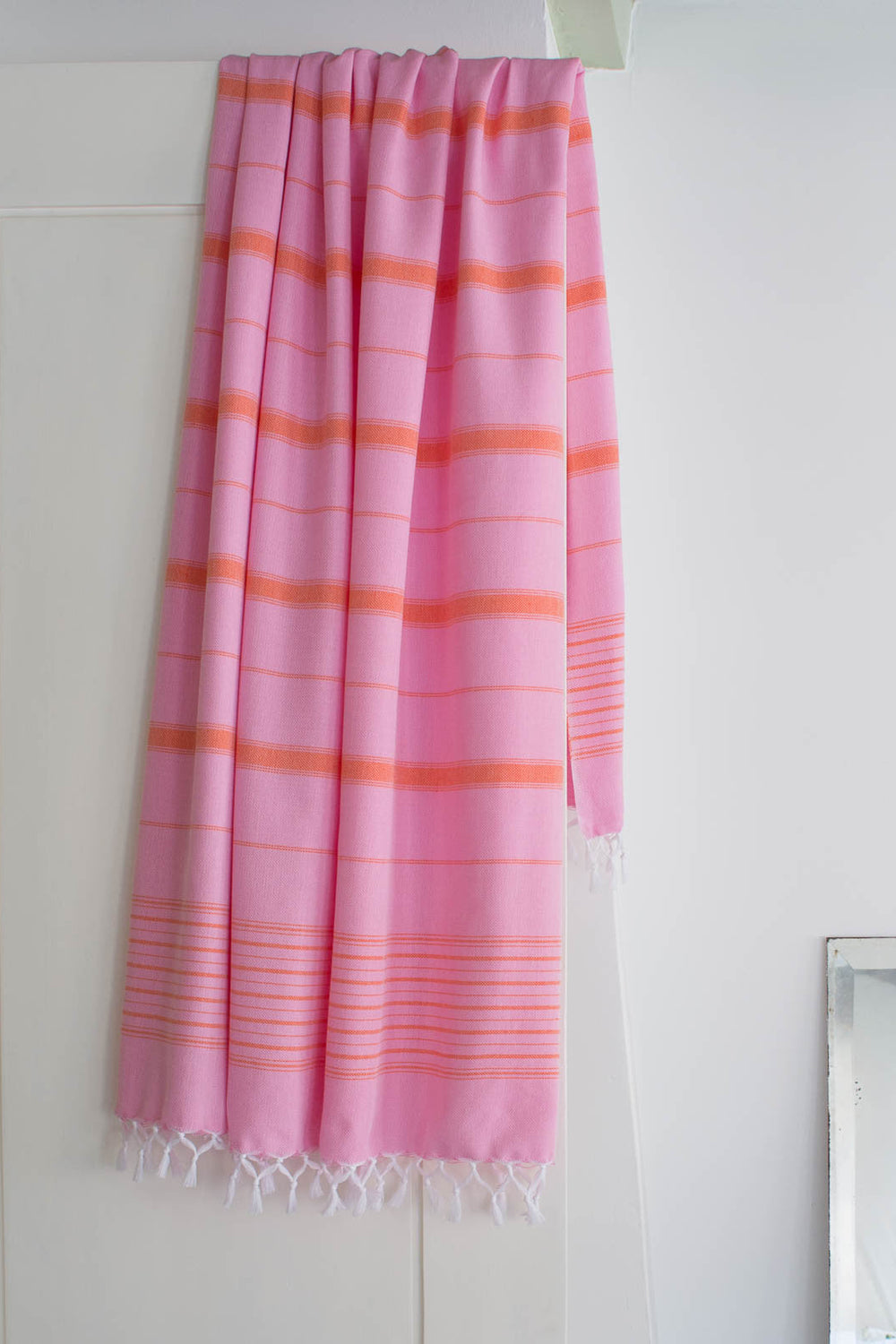 Pink and orange striped towel hanging on a white door