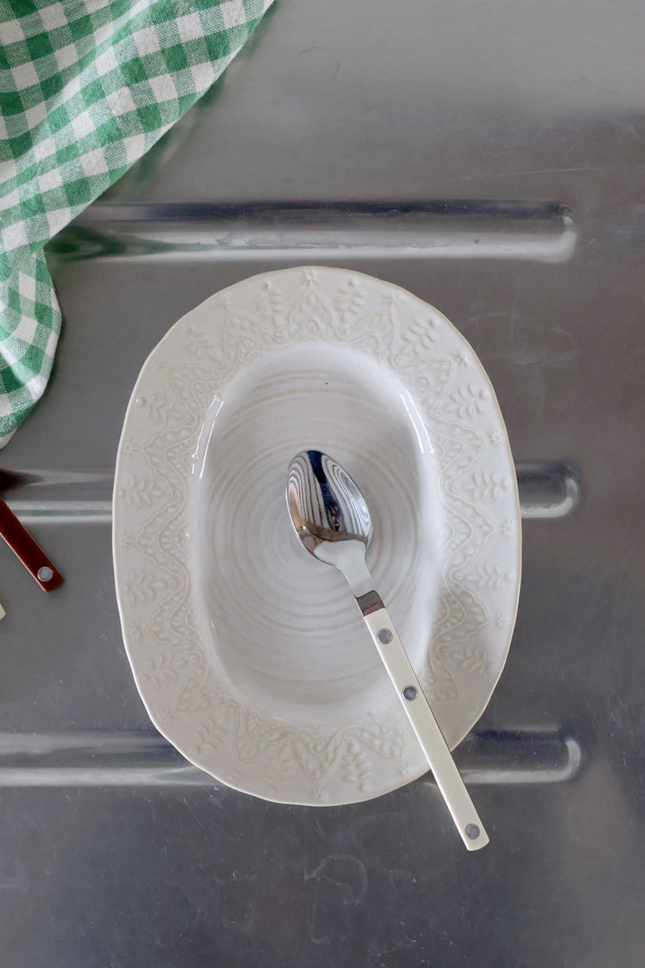 White plate with a spoon on a metallic surface