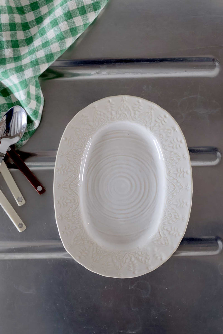 White ceramic plate with decorative patterns on a metallic surface.