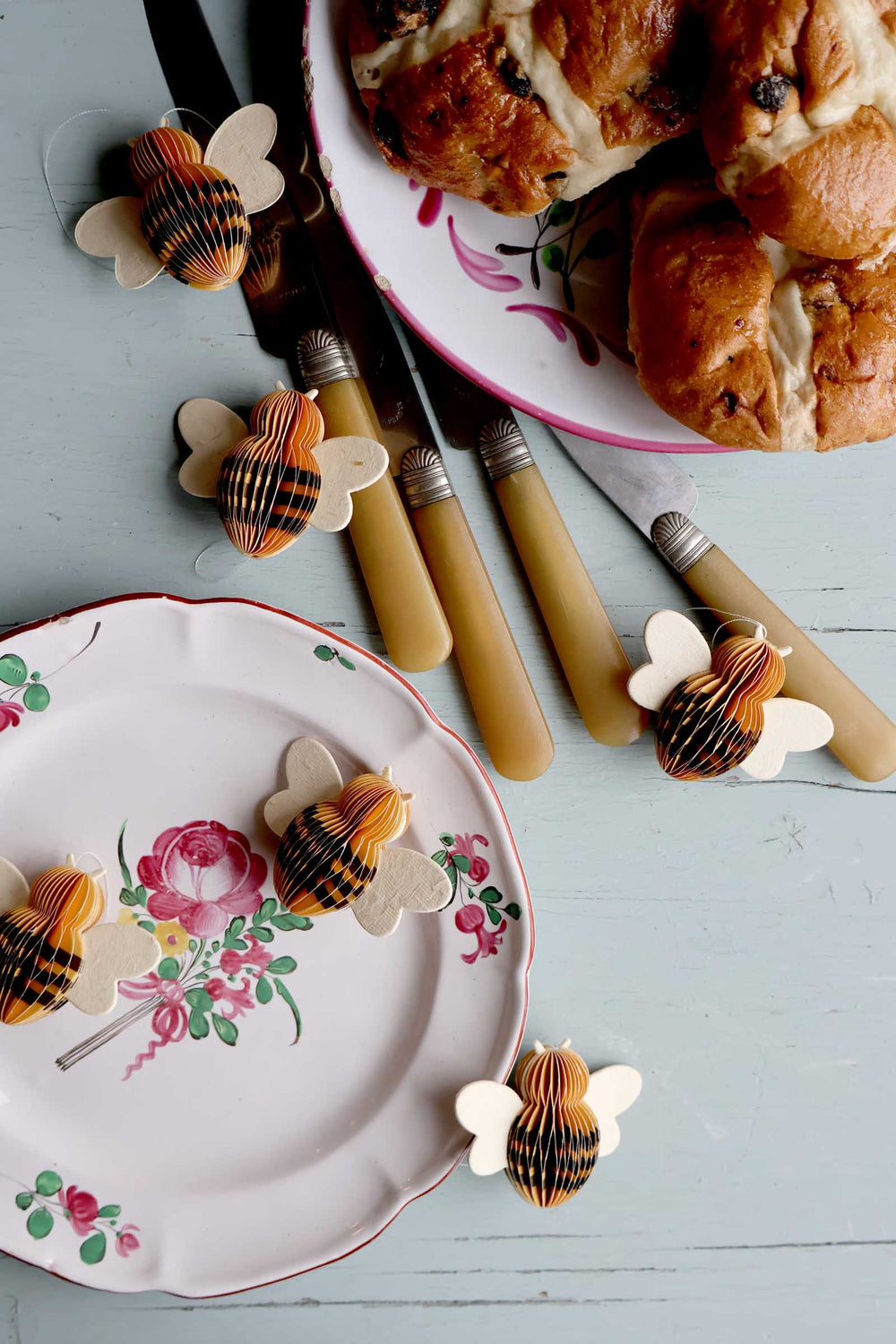 bee easter decorations on a floral plate and bread on a blue surface