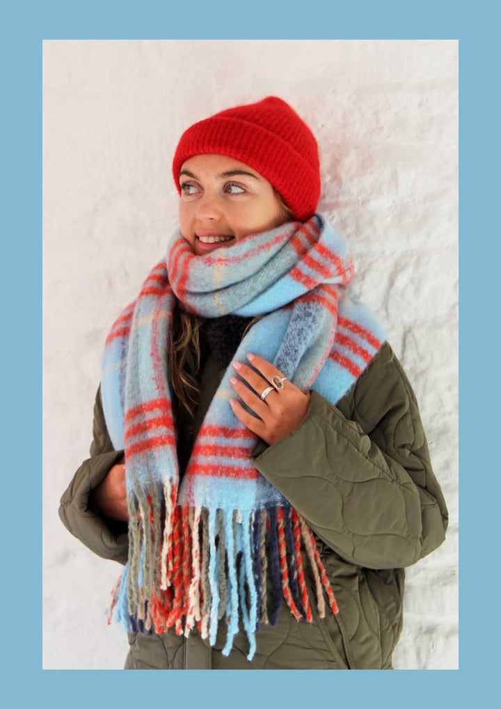 Person wearing a red beanie and a colorful scarf against a light background