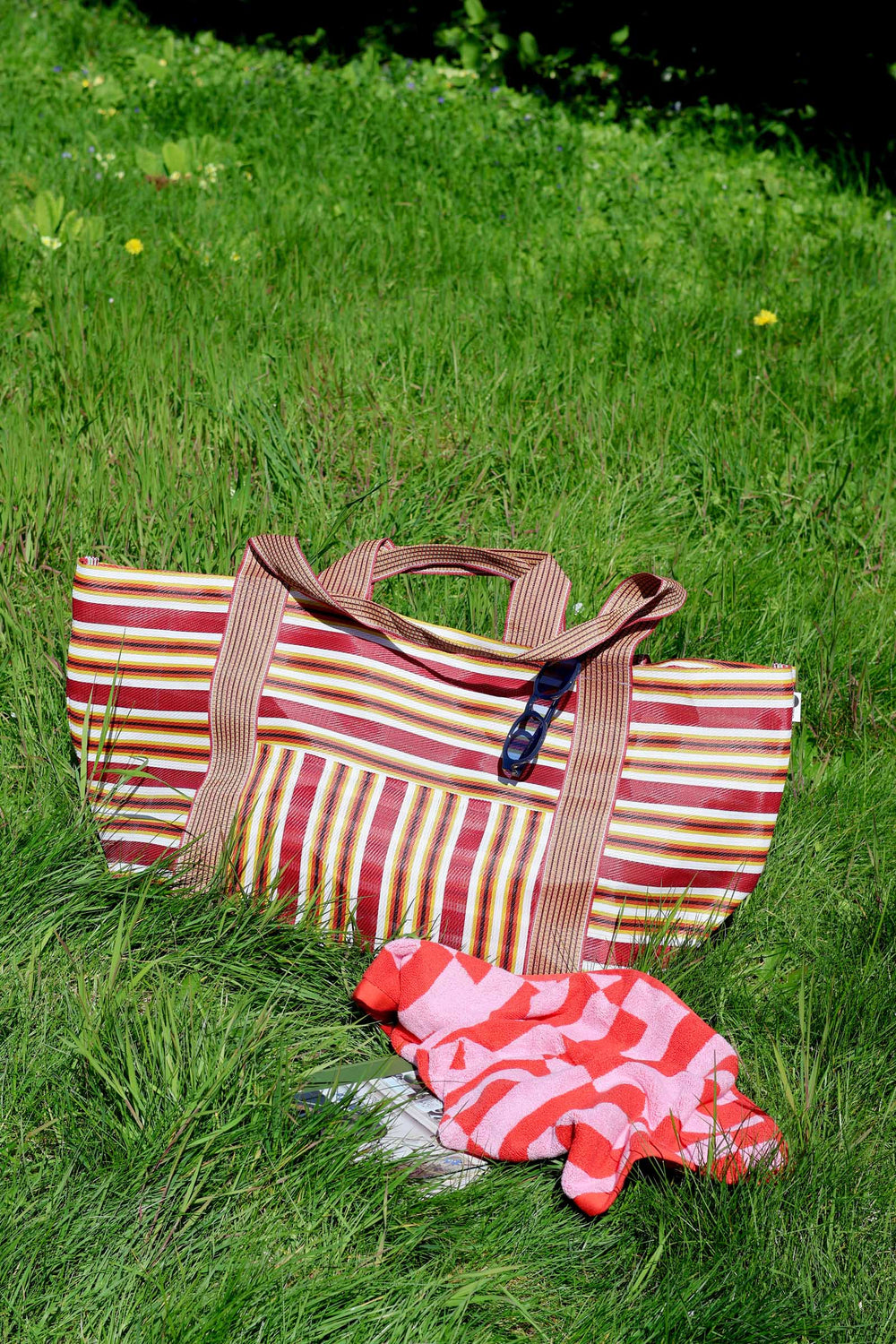 Striped tote bag and matching pouch on grass