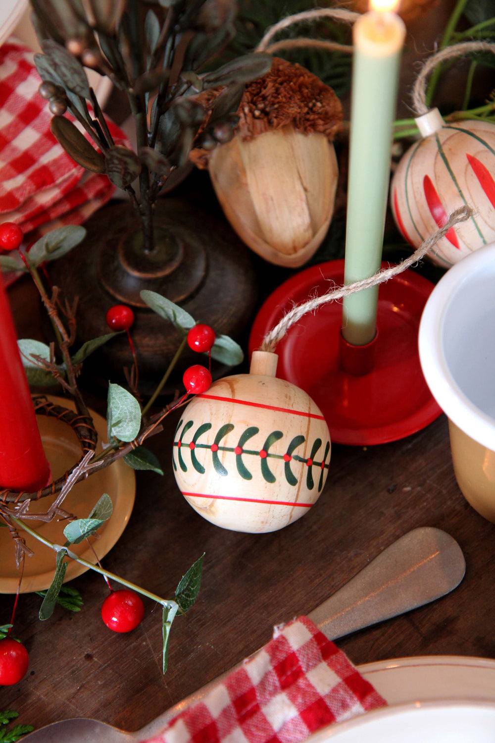 Decorative Christmas table setting with ornaments, candles, and red checkered cloth.