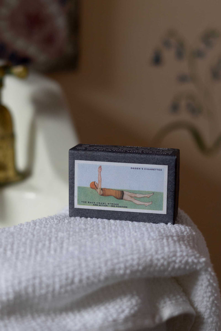 A vintage-style matchbox with an illustrated label reading &