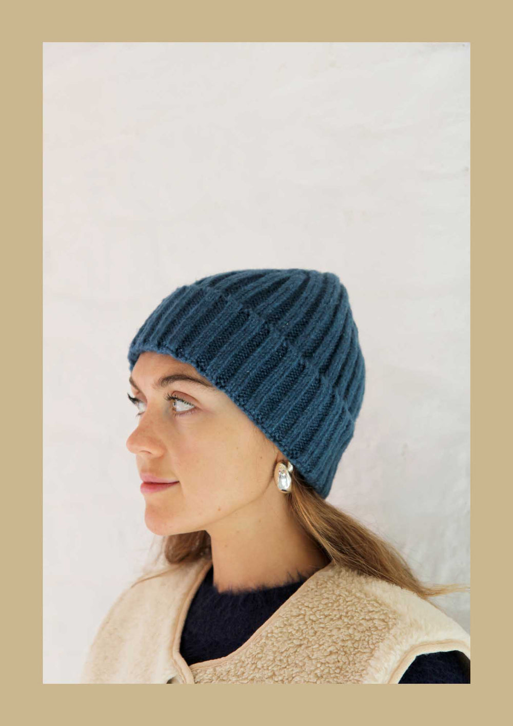 Woman wearing a blue knitted hat against a plain background