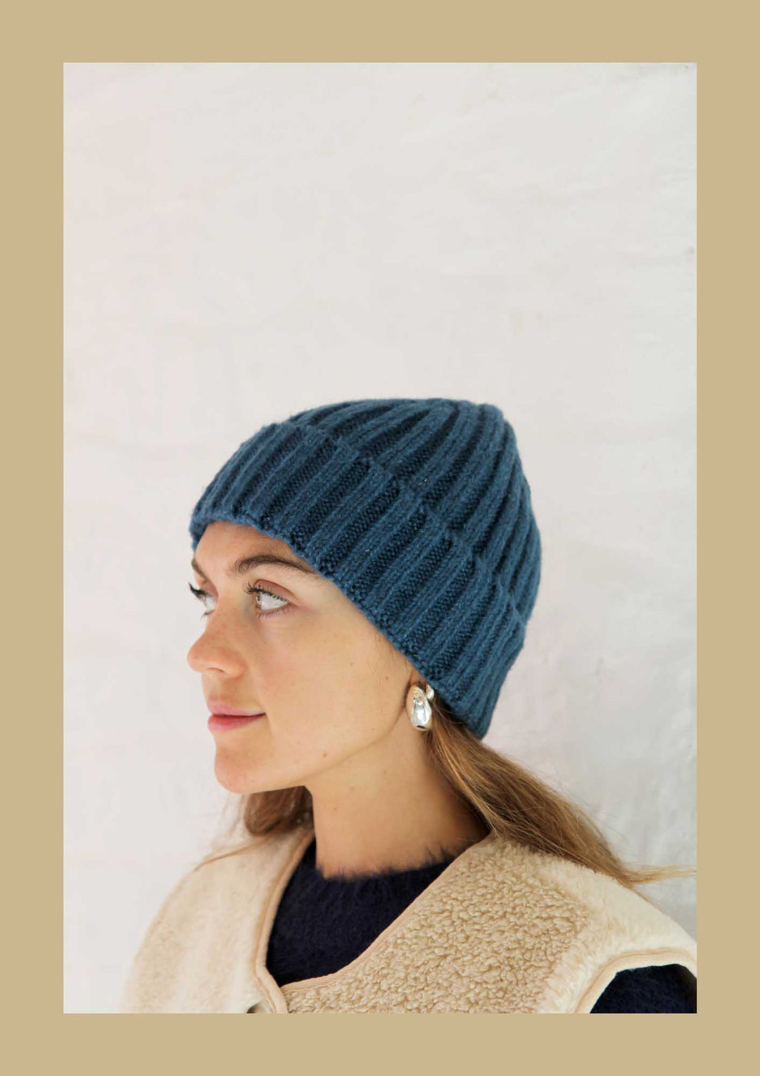 Woman wearing a blue knitted hat against a plain background