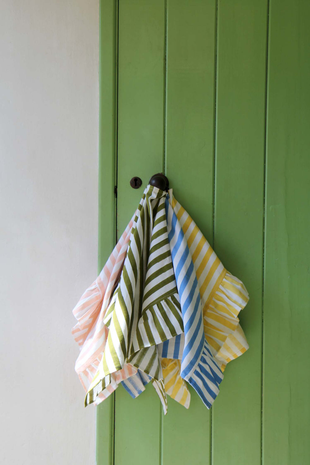 Colorful striped towels hanging on a green door