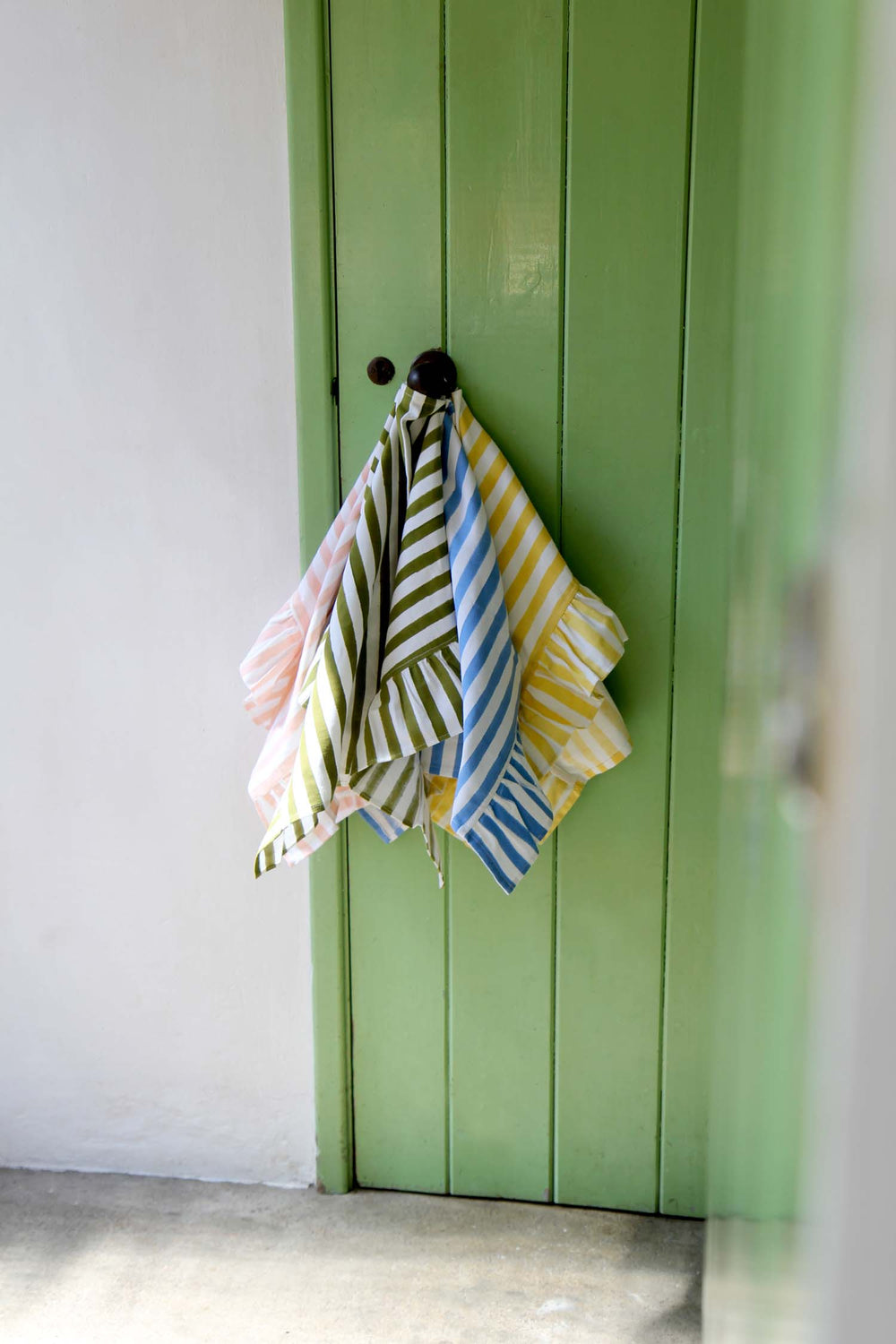 Colorful striped towels hanging on a green door
