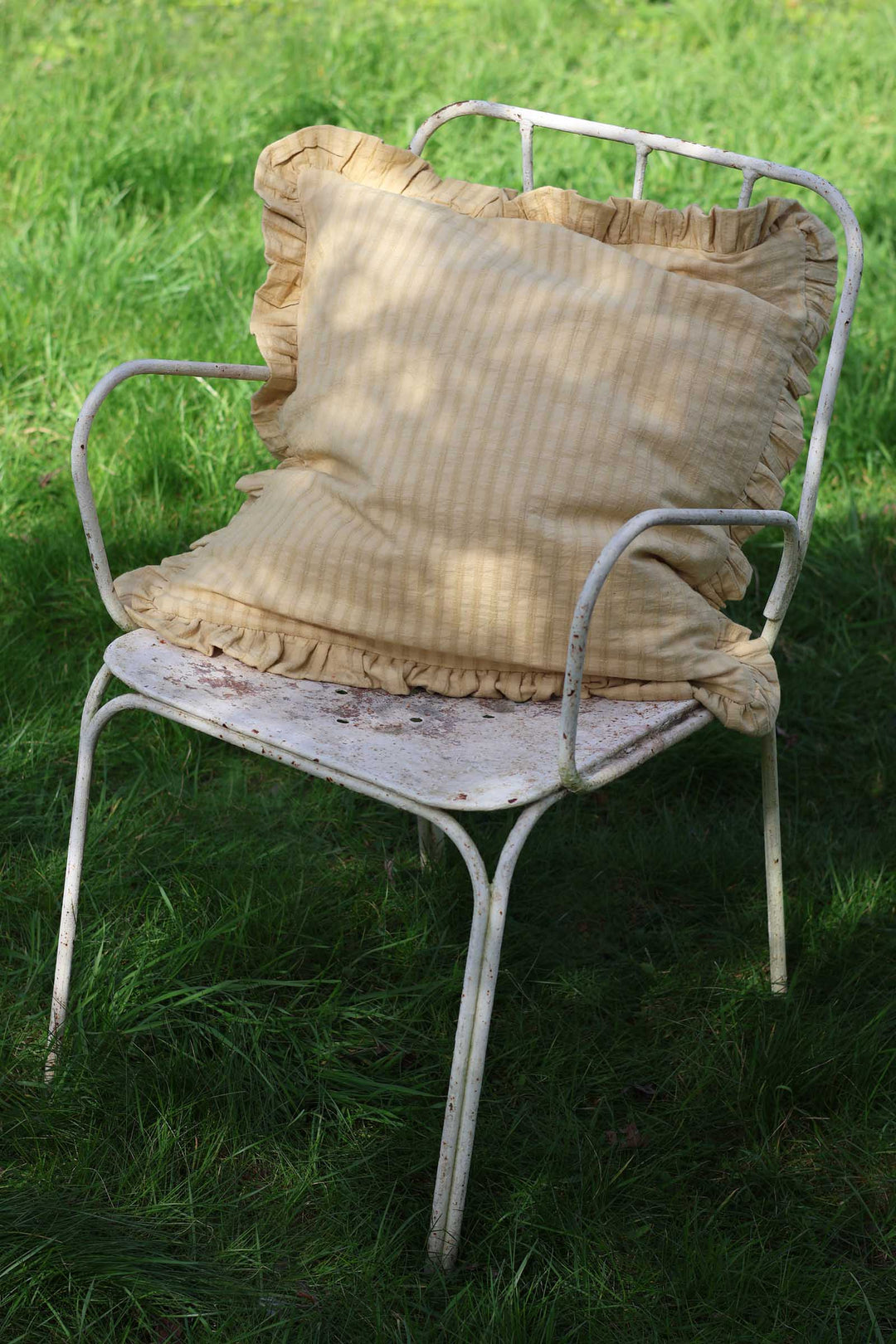 Vintage metal chair with ruffled cushions on a grassy background