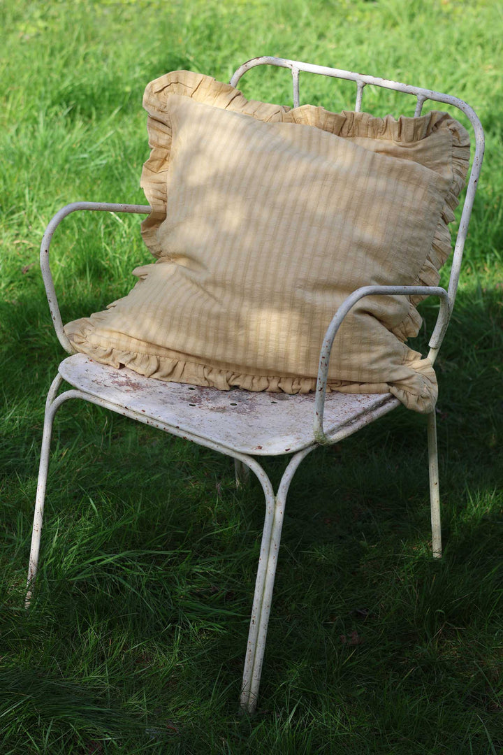 Vintage metal chair with ruffled cushions on a grassy background