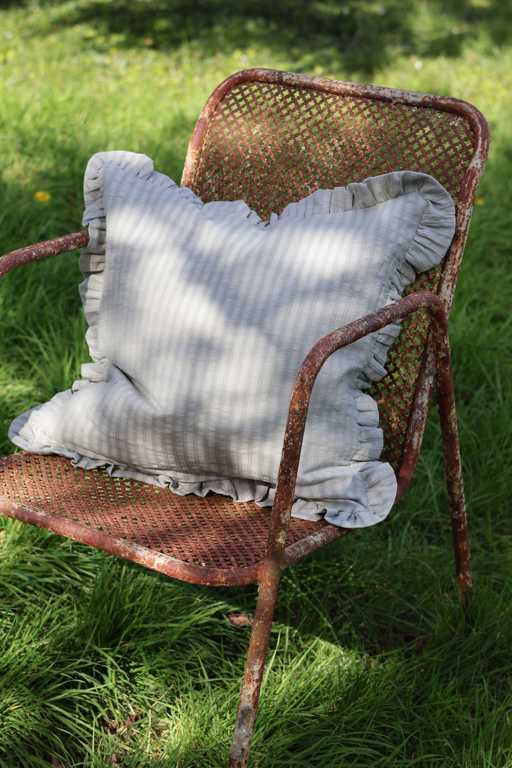 Rustic chair with a textured pillow on a grassy background