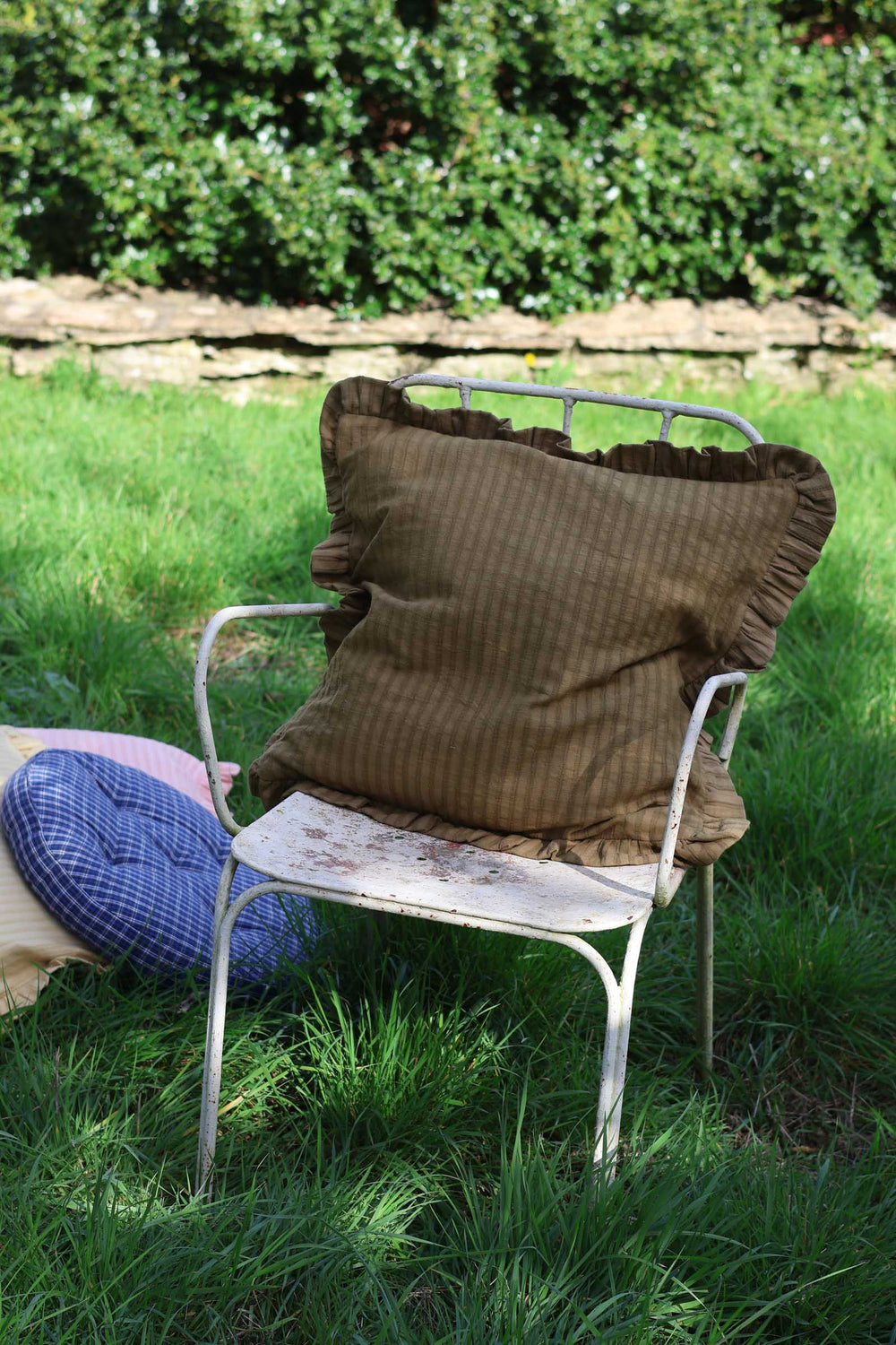 Brown cushion on a metal chair in a grassy outdoor setting