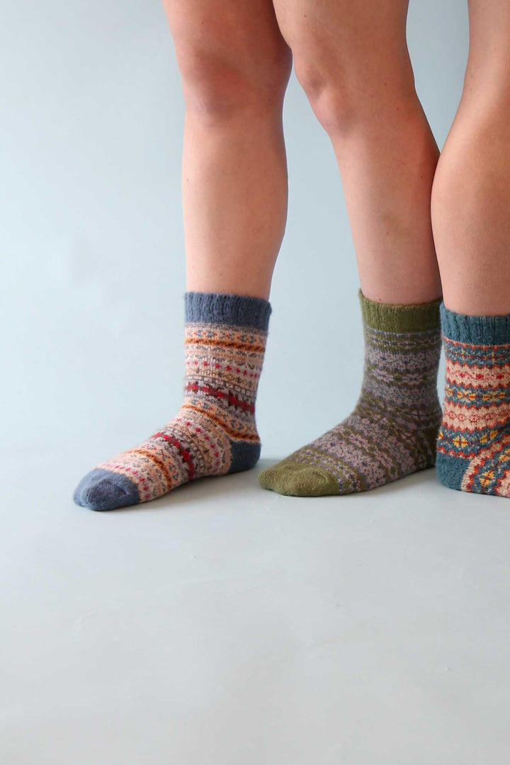 Two pairs of patterned socks worn on feet against a light background