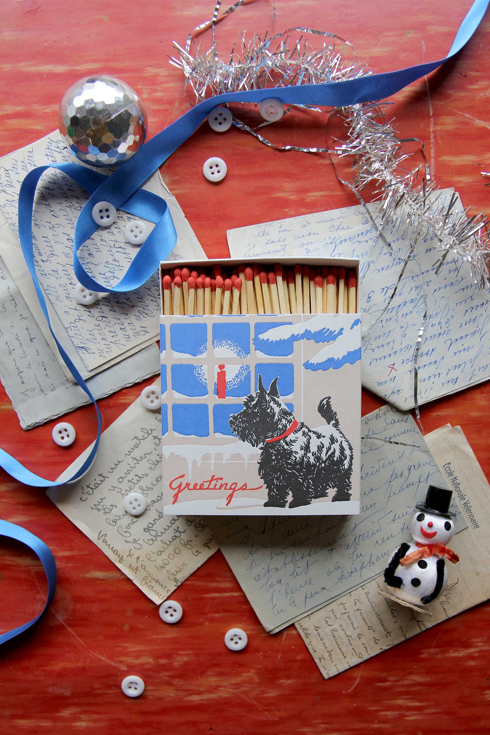 Matches with a dog illustration on a festive background with ribbons and buttons.