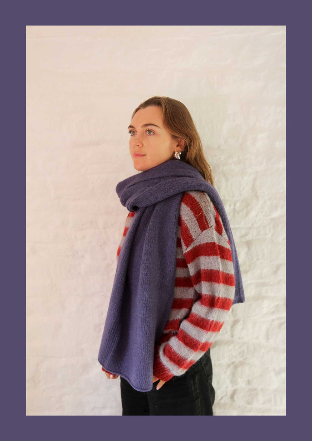 Person wearing a purple scarf and red and white striped sweater against a light background