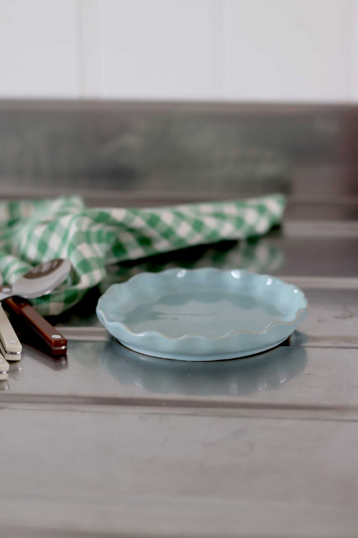 Light blue ceramic plate on a marble surface with a green checkered cloth in the background.