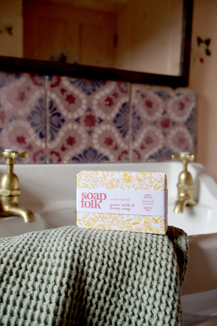 Bar of soap on a towel with 'soap folk' packaging in a bathroom setting.