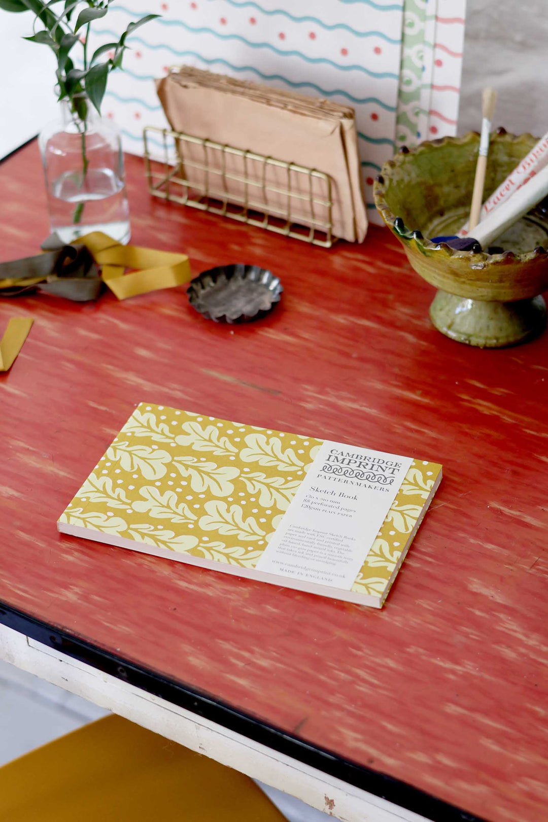 Notebook with floral design on a red surface with decorative items.