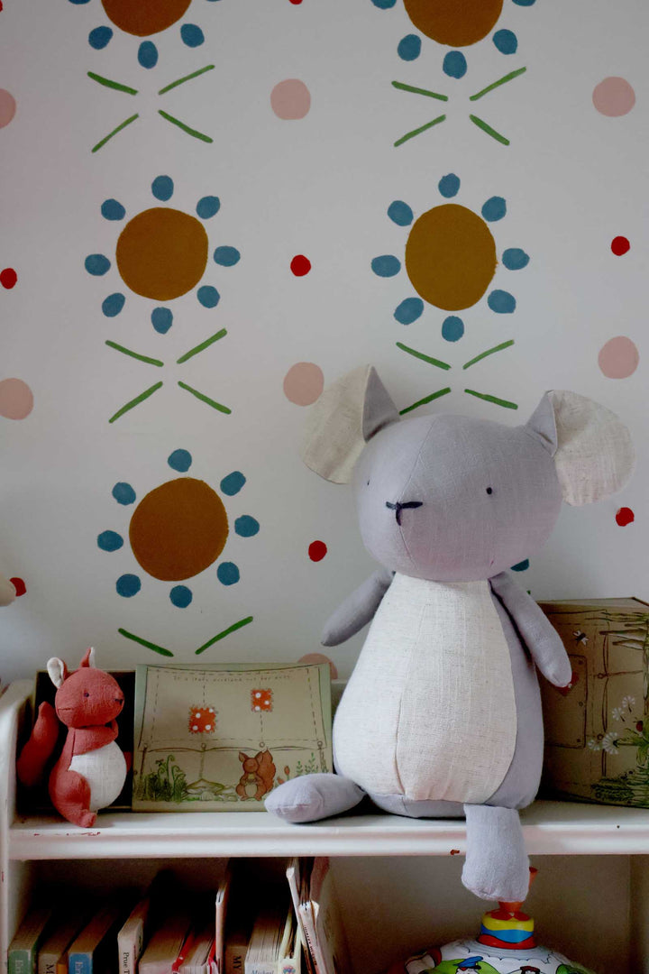 Plush toy mouse on a shelf with decorative wall stickers in a child's room
