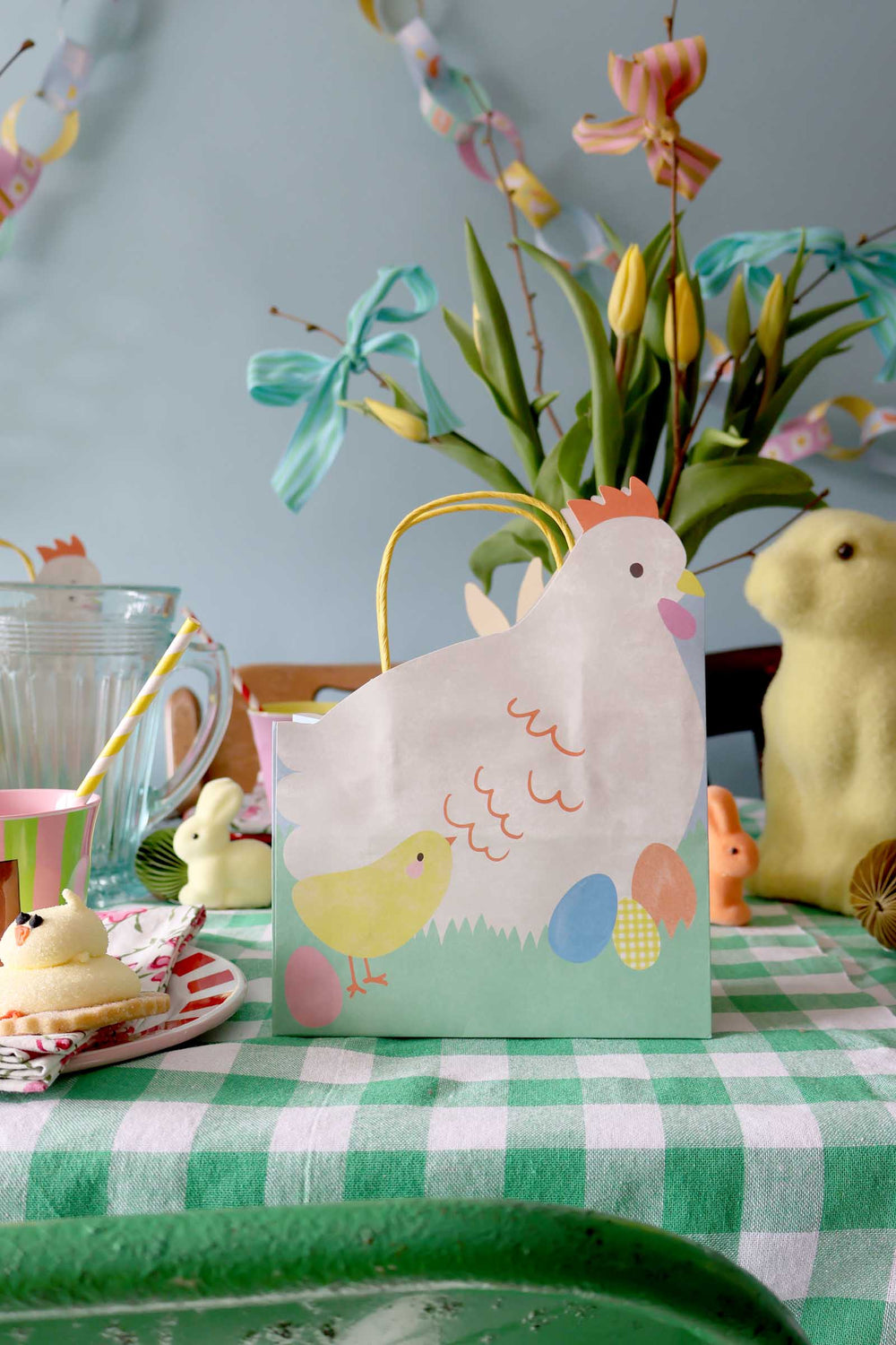 Decorative Easter gift bag with a chicken design on a table with Easter decorations.
