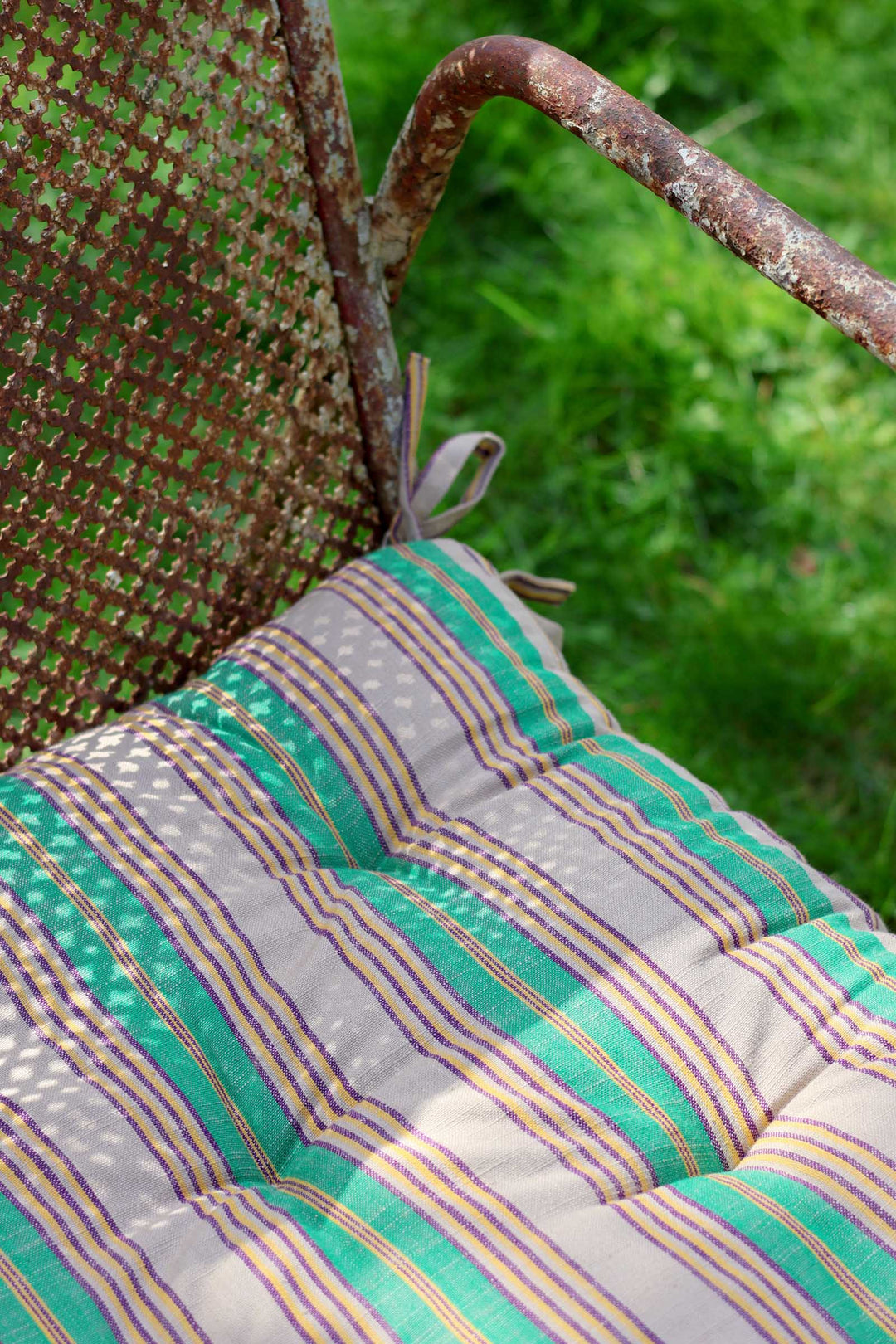 Striped cushion on a metal chair with grass in the background