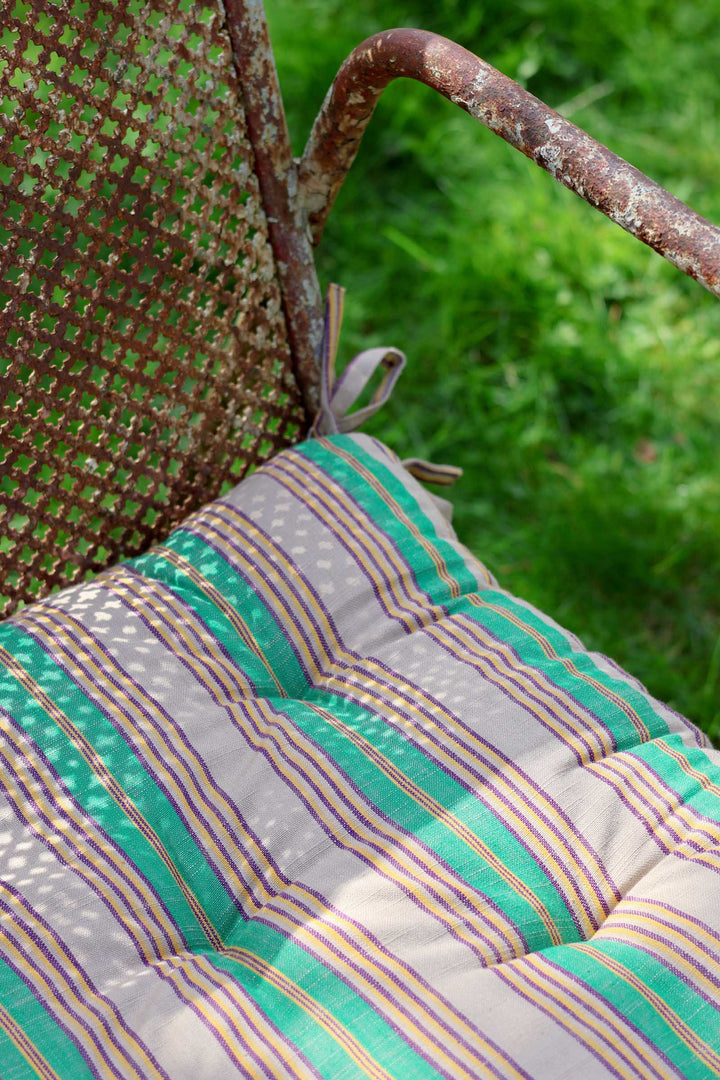 Striped cushion on a metal chair with grass in the background