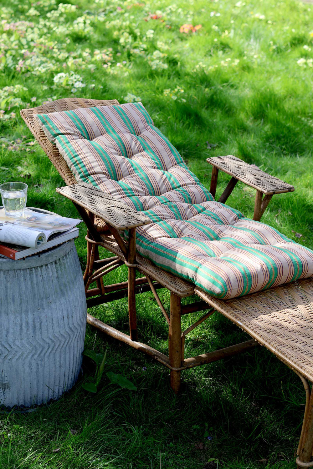 Wicker chair with striped cushions on a grassy outdoor setting