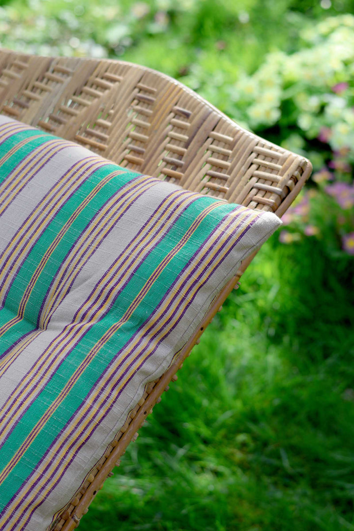 Wicker chair with striped cushion in a garden setting