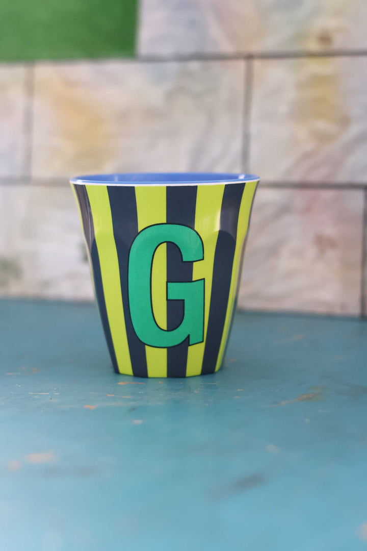 Cup with green letter 'G' on a blue surface