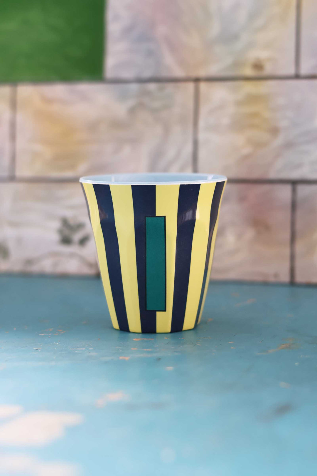 Striped cup with green interior on a blue surface