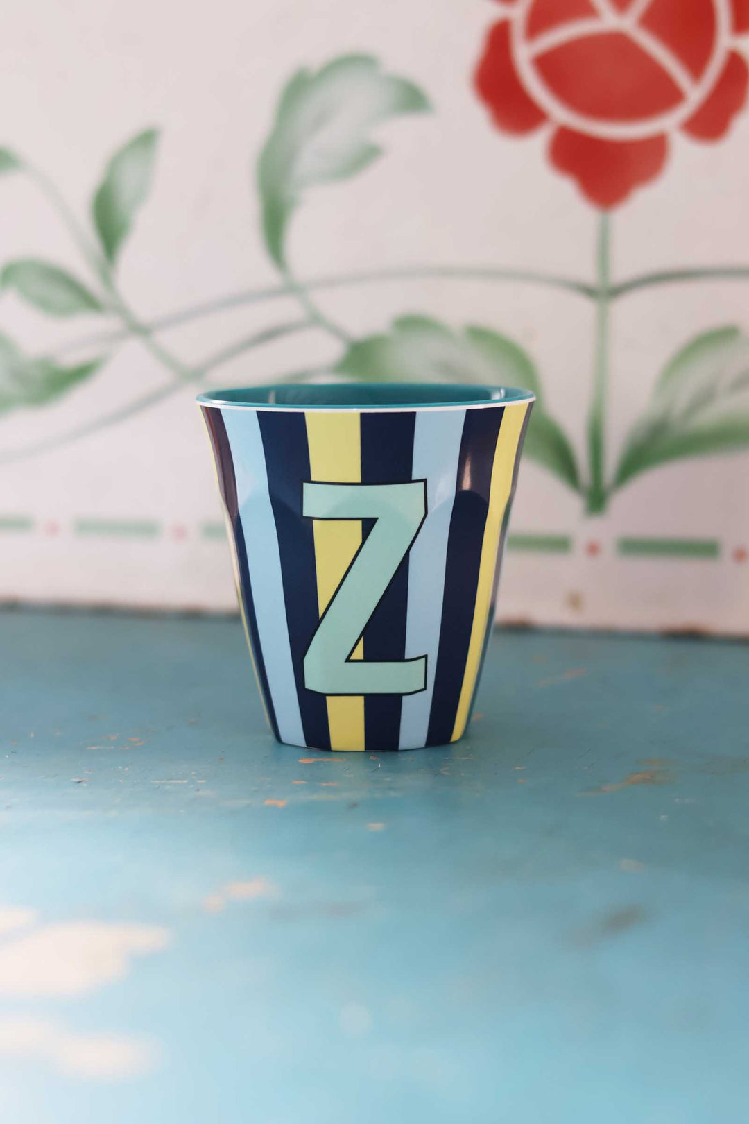 Colorful striped cup with letter 'Z' on a blue surface