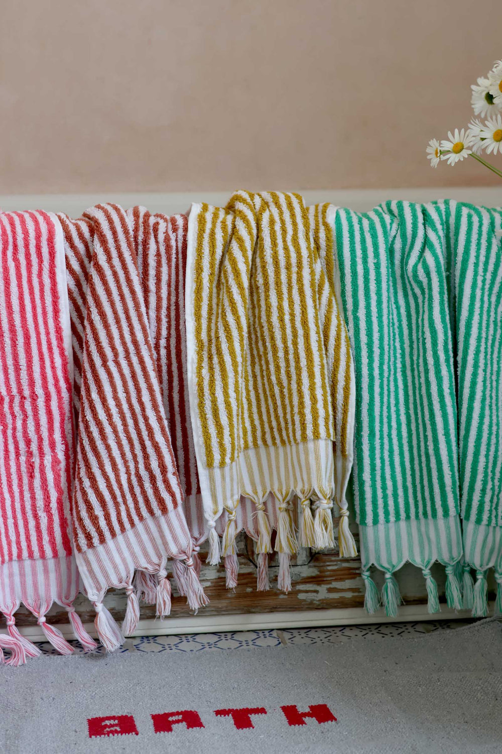Colorful striped towels hanging on a rack with a neutral background