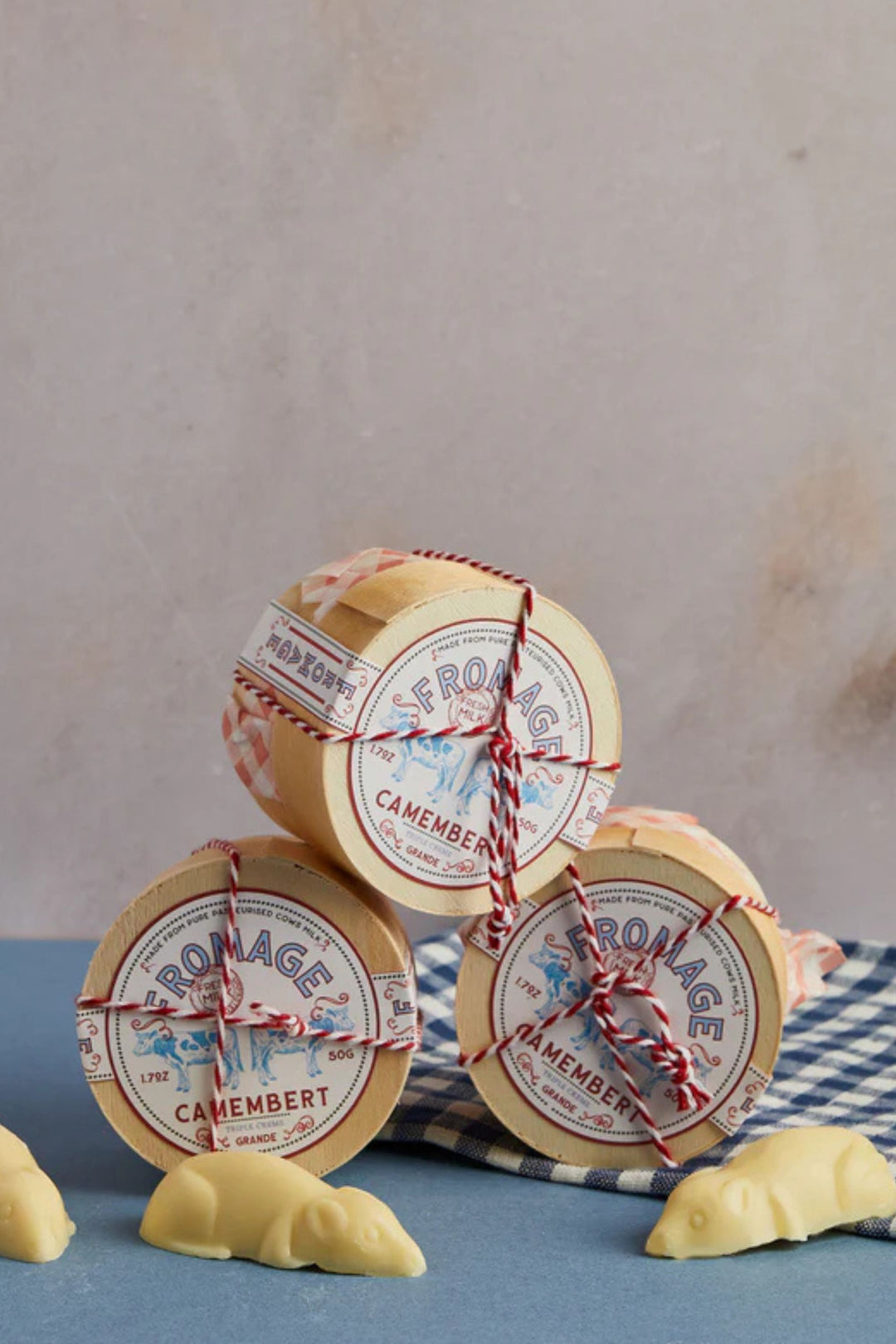 Chocolate Camembert cheese wheels with decorative labels on a blue surface