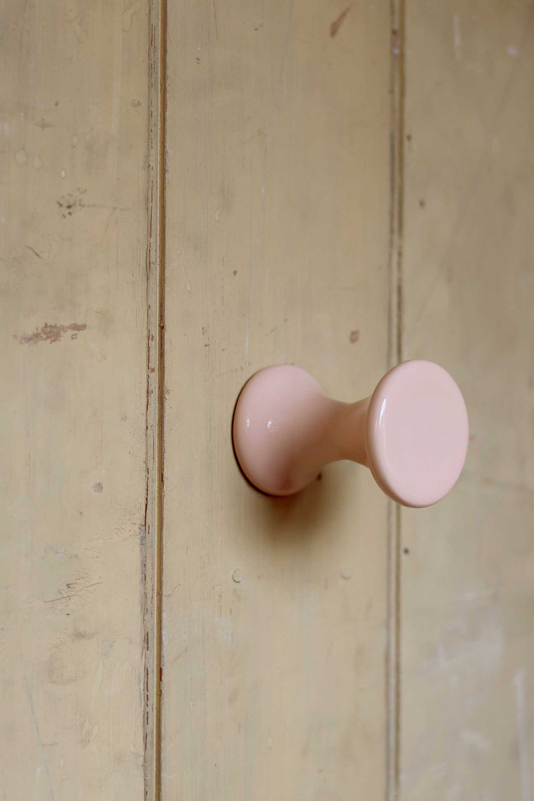 Pink cabinet knob on a wooden door