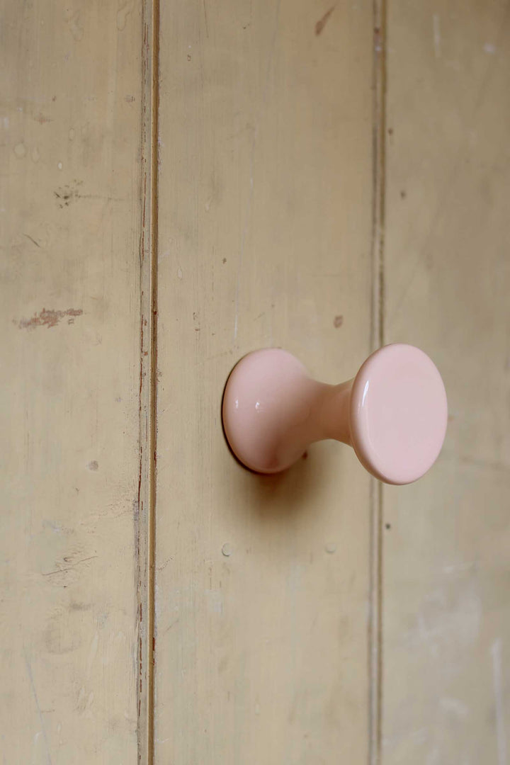Pink cabinet knob on a wooden door