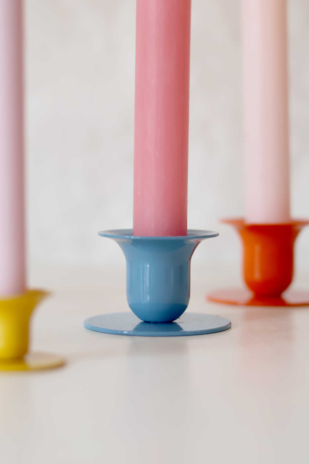 Colorful candle holders with pink candles on a white background