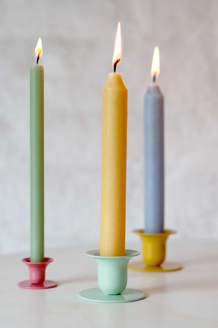 Three colorful candles in holders on a neutral background