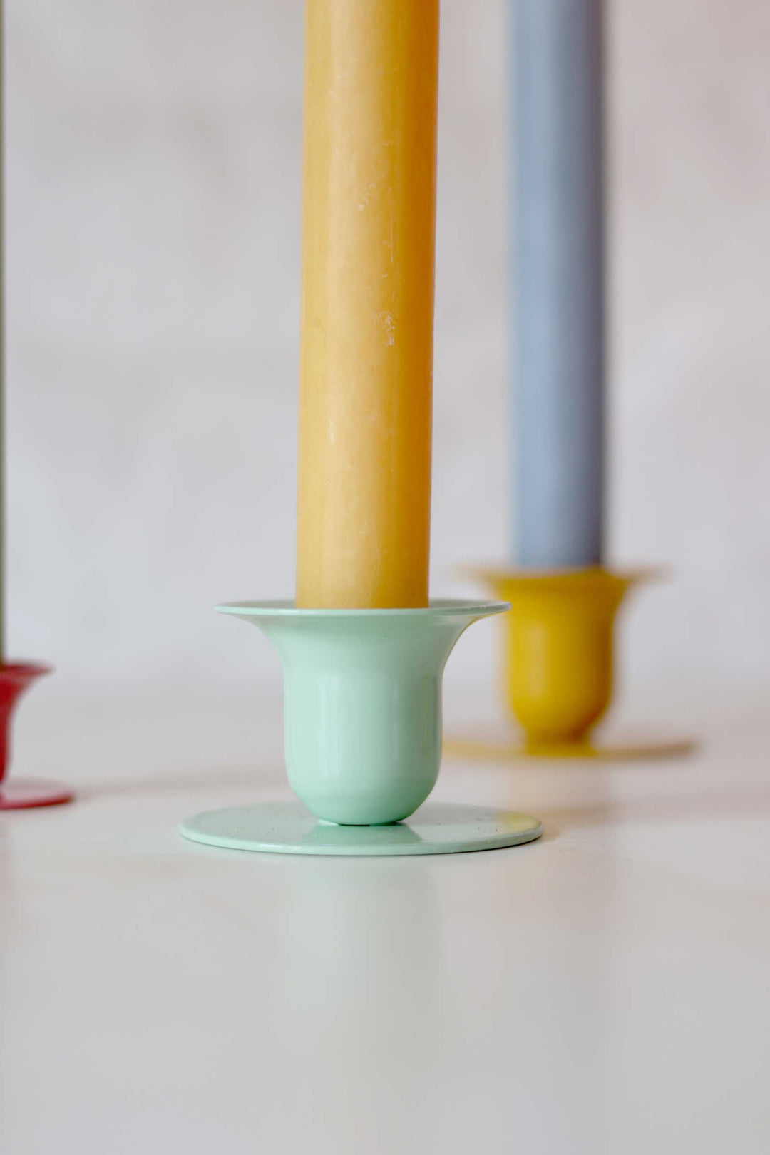 Two candles in holders on a white surface with a light gray background