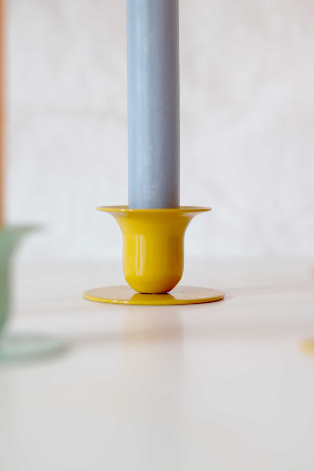 Yellow candle holder with a gray candle on a white surface