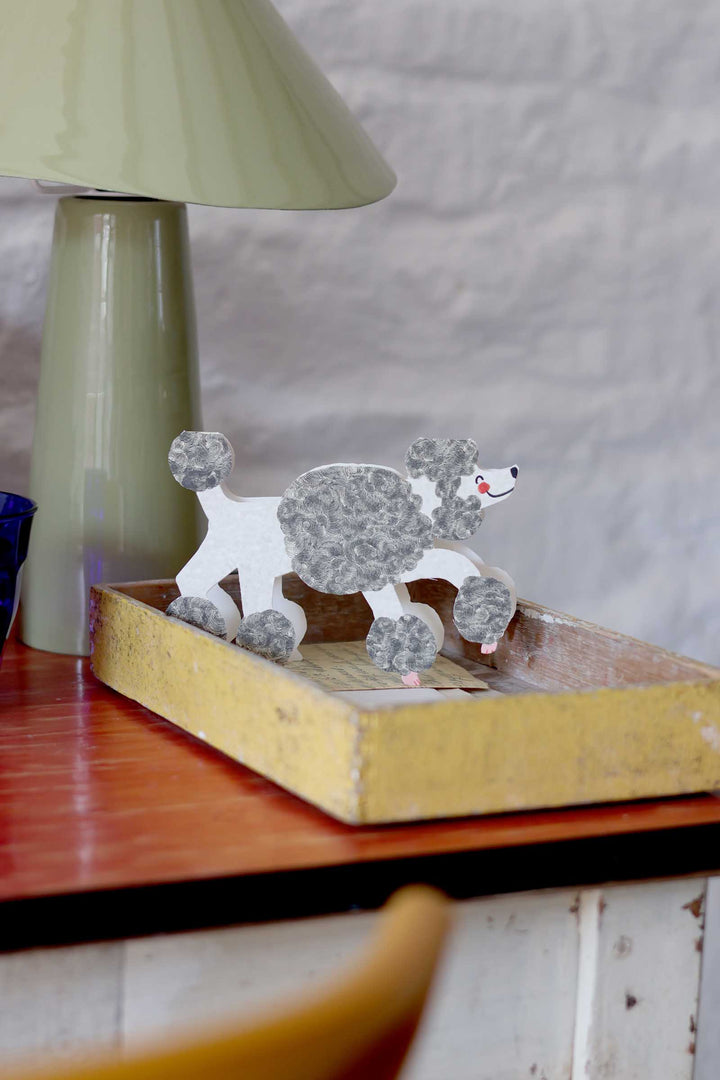 poodle card on a wooden tray with a lamp in the background