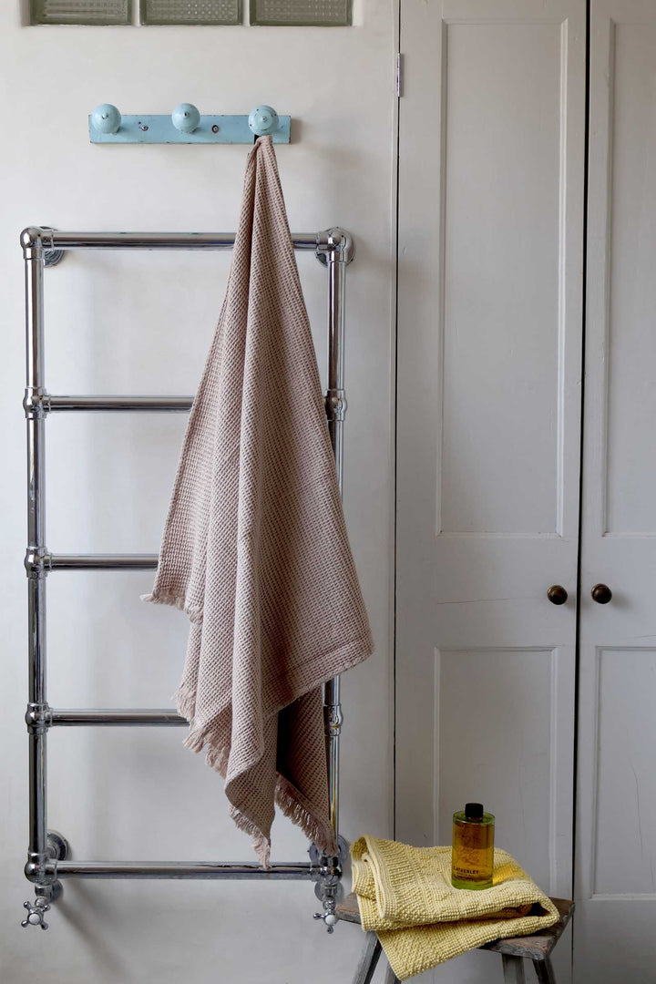 Towel rack with towels and a bottle of oil against a white door.