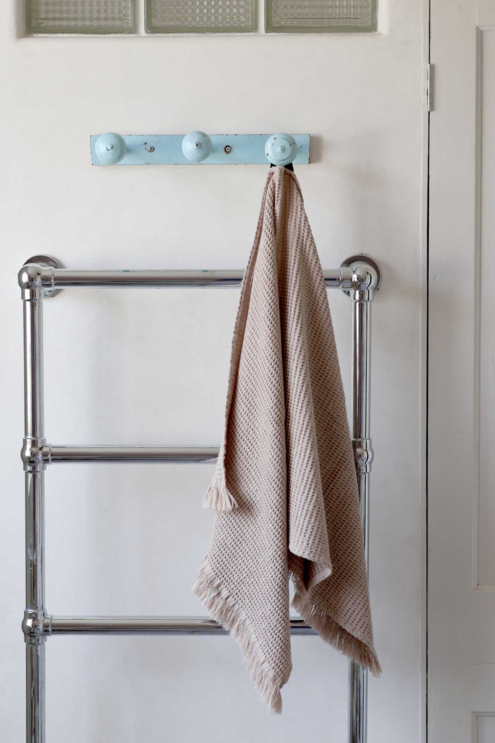 Towel hanging on a metal towel rack against a white wall.
