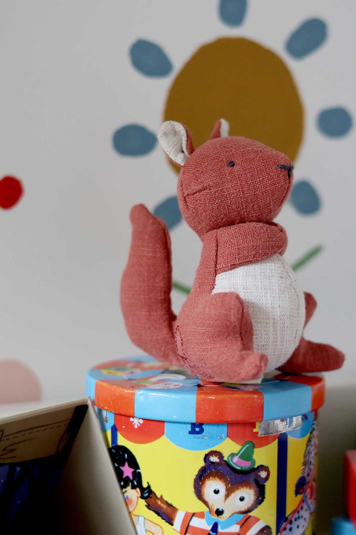 Red plush fox toy on a colorful box with a polka dot background