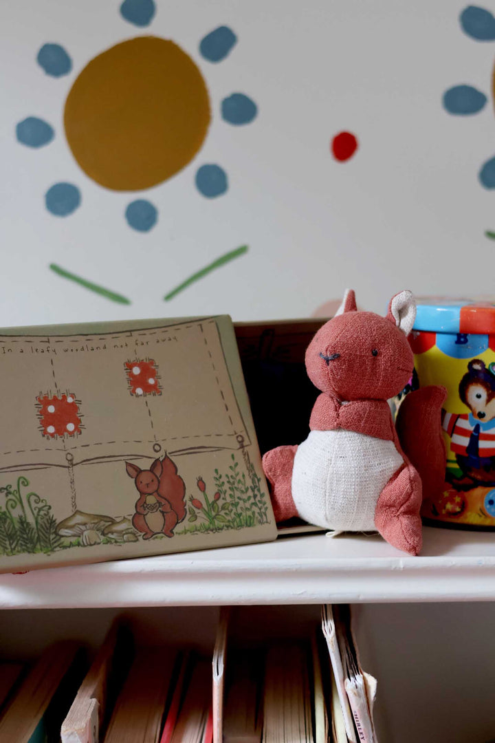 Plush toy and children's book on a shelf with colorful wall art in the background